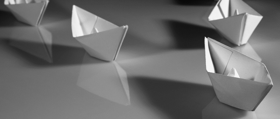 Line of paper boats symbolizing financial dangers in the retirement journey.